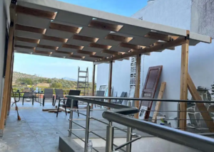 Κατασκευή πέργκολας με ξύλο σε χρώμα και ύφασμα εκρού διάτρητο